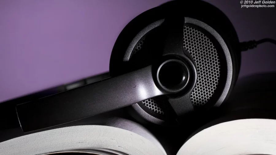 Black over-ear headphones resting across the pages of an open paperback, the audiobooks vs reading choice in one picture