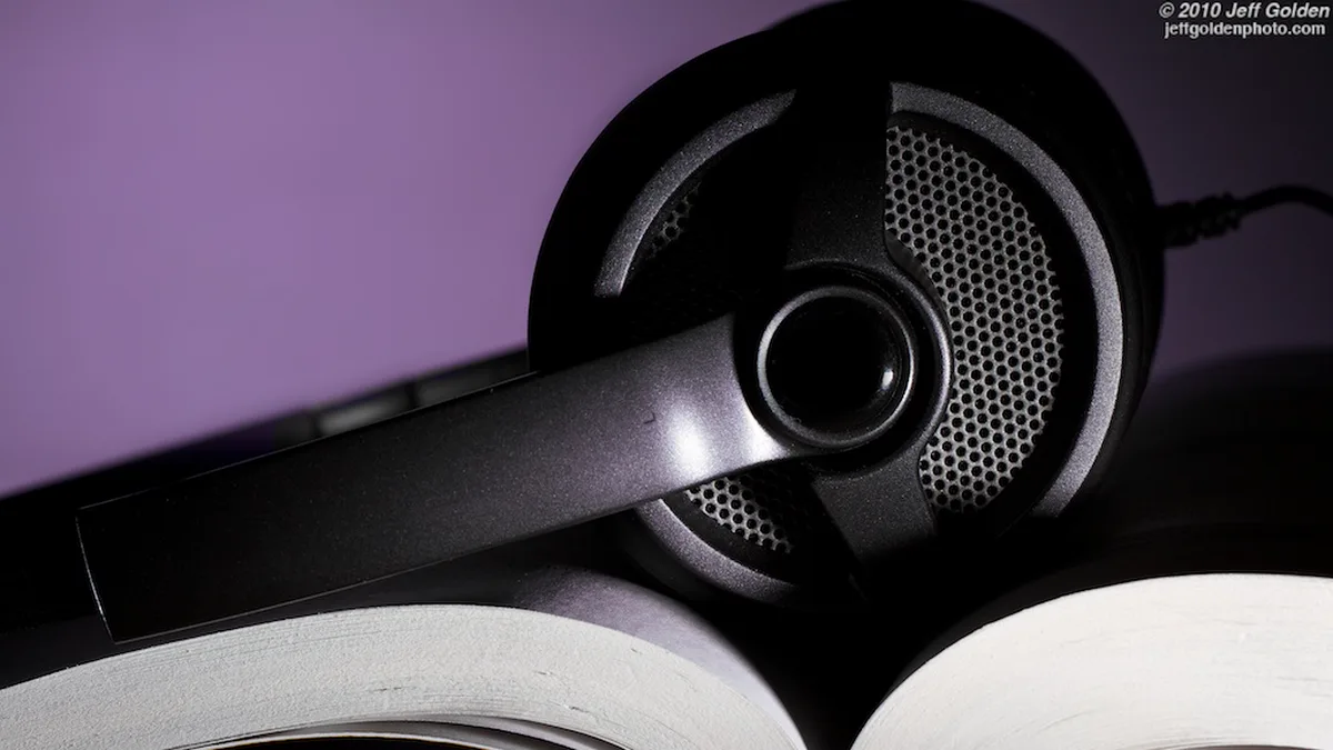 Headphones Resting on an Open Paperback Black over-ear headphones resting across the pages of an open paperback, the audiobooks vs reading choice in one picture