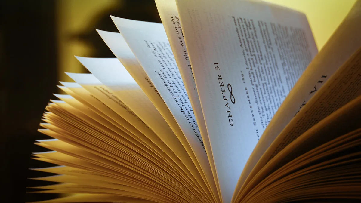 Book with Pages Fanned in Lamplight Close-up of an open book with pages fanned out in warm light, a reminder that a yearly book count is built page by page
