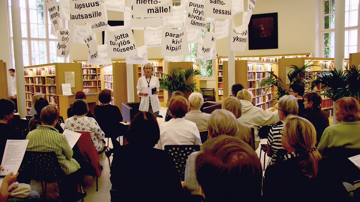 Library Reading Group Meeting Between the Shelves Rows of adults seated in a bright public library listening to a group leader, a library-hosted option when you start a book club