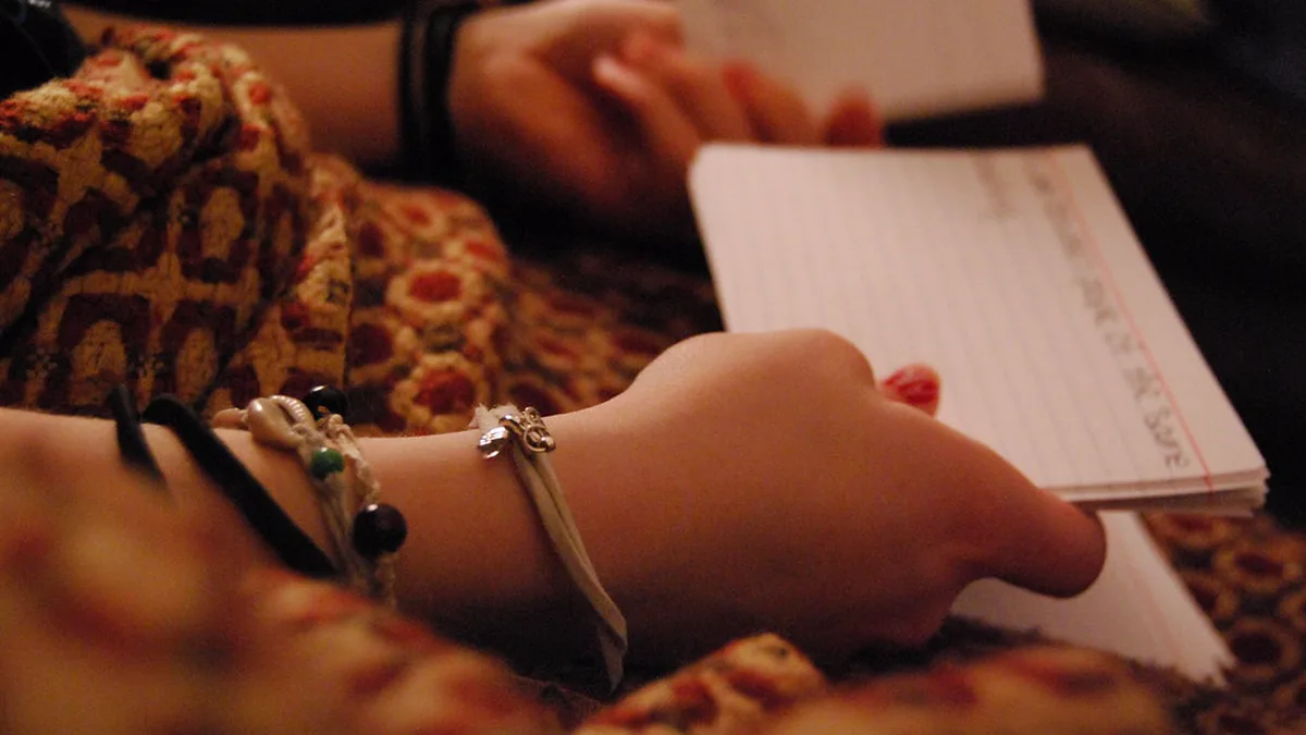 Handwritten Index Cards Used for Self-Testing Close view of hands holding a stack of lined index cards with handwritten notes, the kind of cards used for retrieval practice