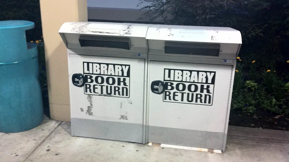 Library Book Return Boxes for Unfinished Reads Two grey library book return drop boxes on a sidewalk outside a branch library, where an unfinished borrowed book can go back with no questions